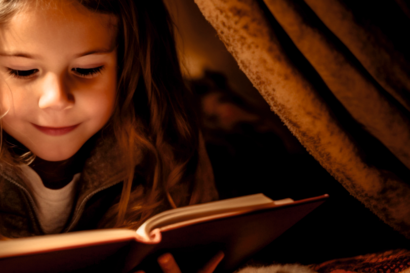 Das Bild zeigt ein Mädchen beim Lesen eines Buches.