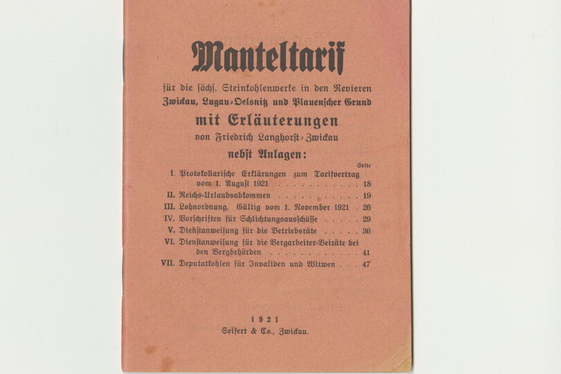 Zu sehen ist ein Bild eines Manteltarifs. Der Umschlag hat eine orange Farbe und ist mit altdeutscher Schrift versehen.