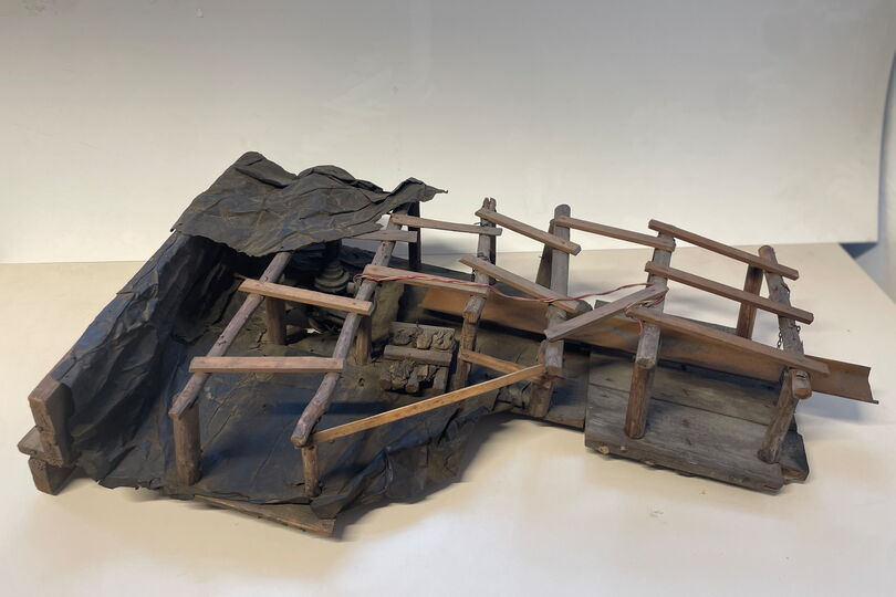 Es ist eine modellhafte Darstellung einer Untertageszene im Steinkohlenbergbau abgebildet. Hierbei sieht man den hölzernen Ausbau. Links befindet sich eine Nachbildung einer Kohlendrehbohrmaschine, rechts die einer Schüttelrutsche.