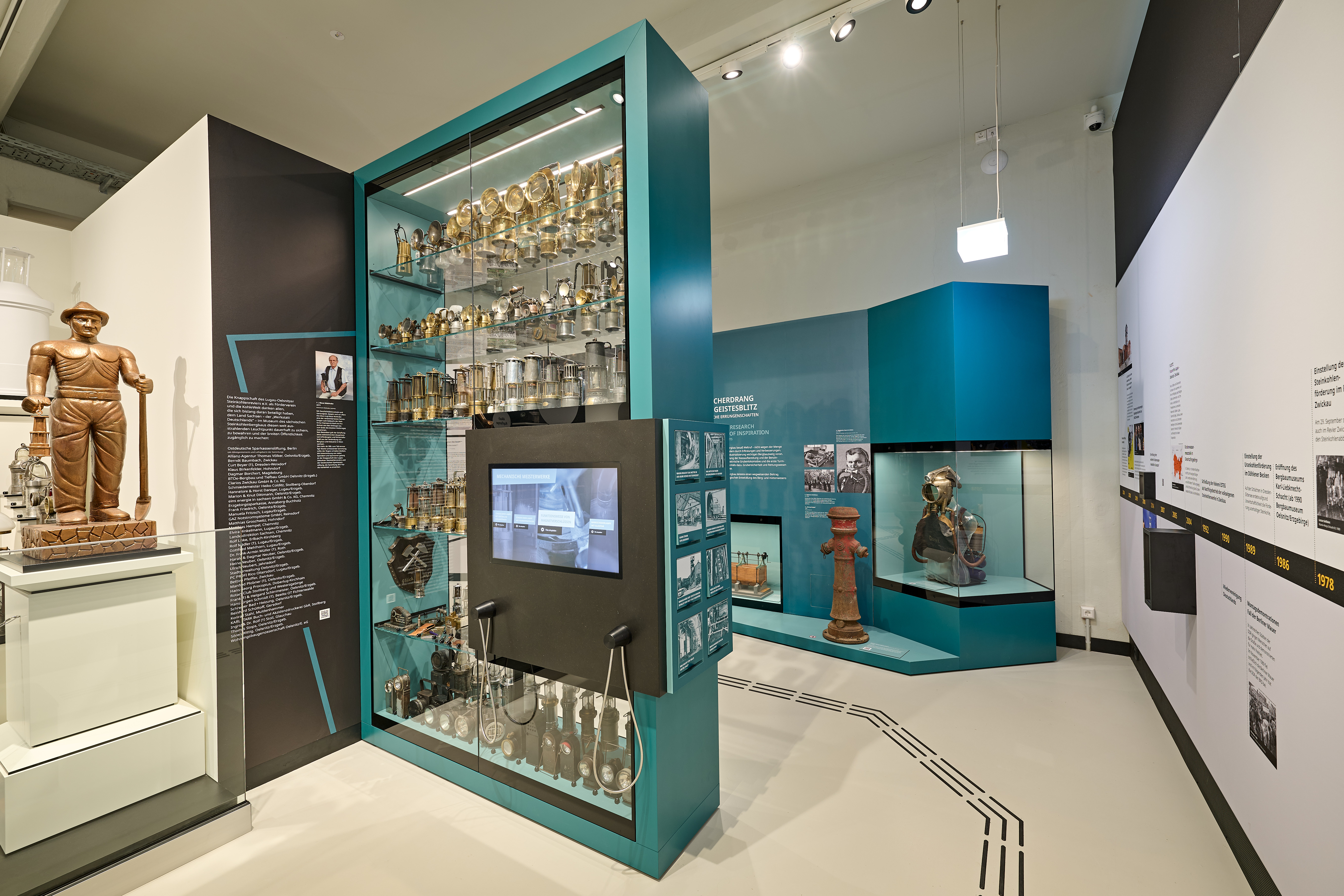 Zu sehen ist ein Ausschnitt aus einem Ausstellungsraum mit einer Vitrine. In dieser Vitrine sind Grubenlampen ausgestellt.